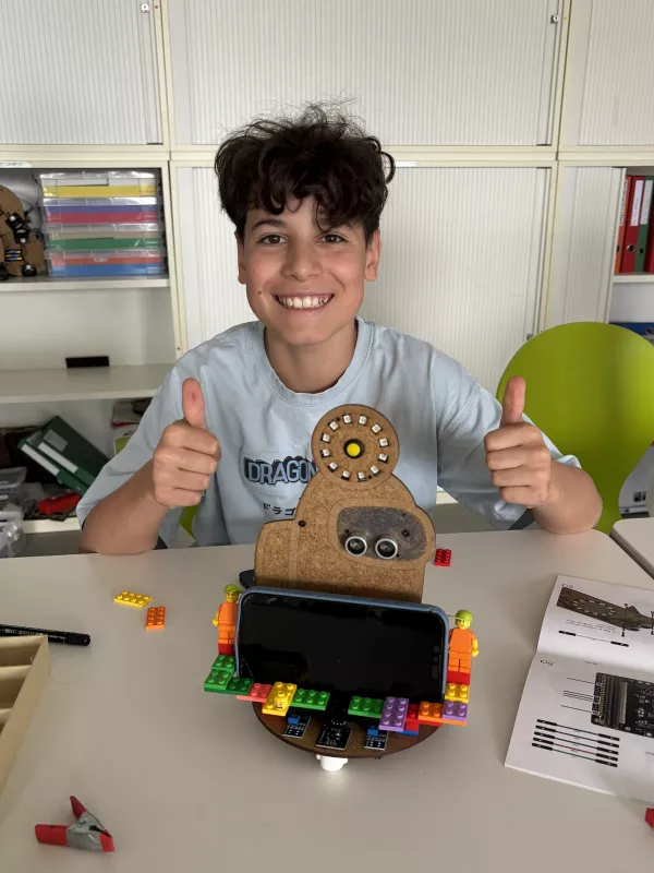 A boy doing thumbs up next to his robot