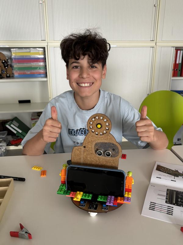 A boy doing thumbs up next to his robot