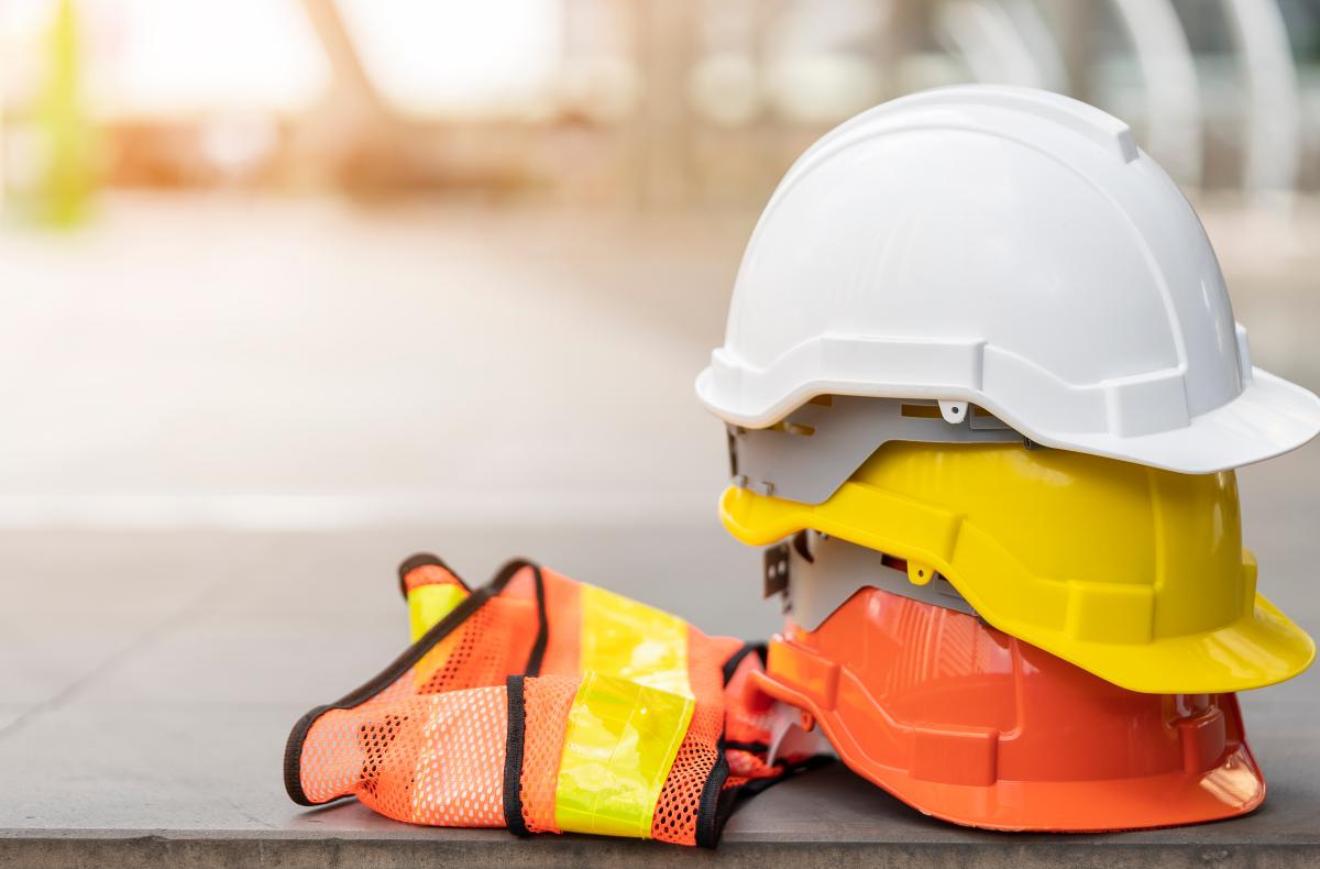 A pile of hard hats and a hi-vis safety vest.