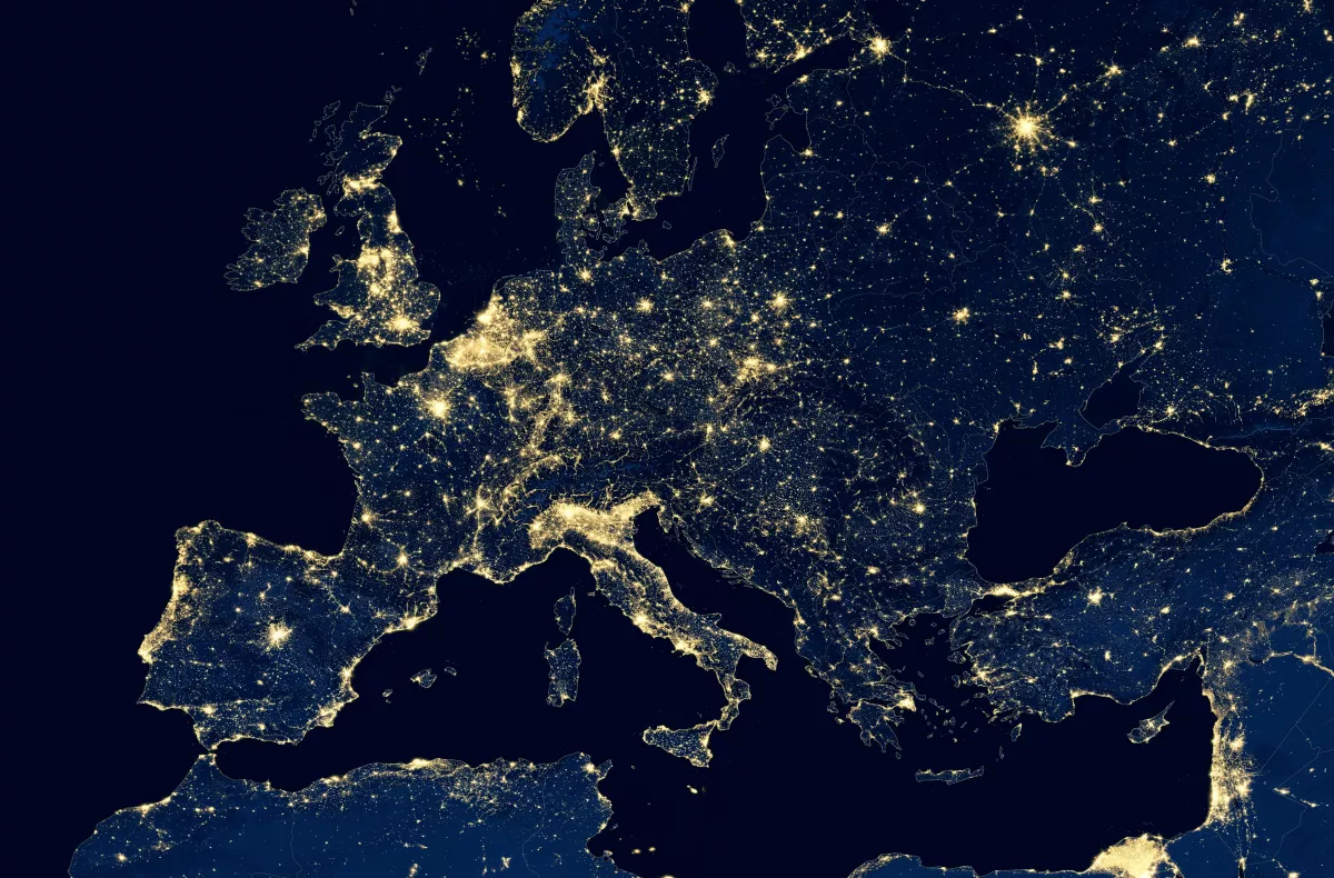 An aerial night view of Europe, showing the dense concentration of the electricity network.