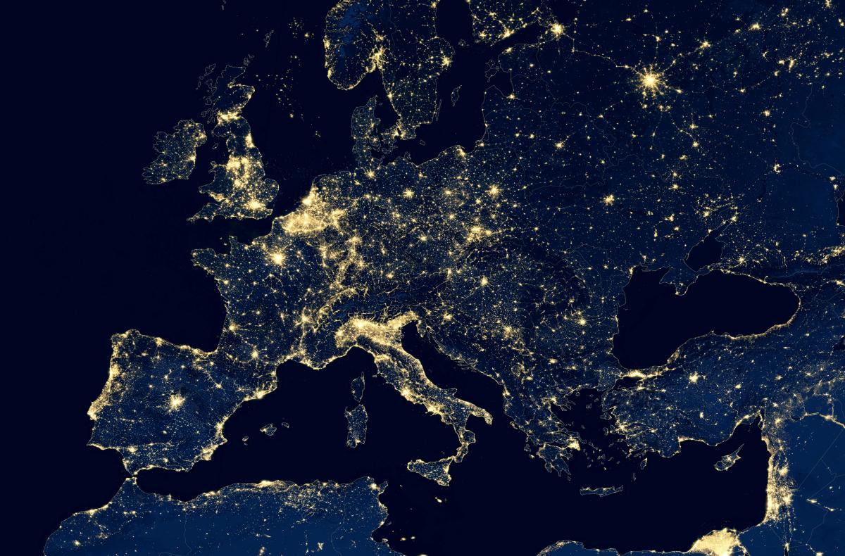 An aerial night view of Europe, showing the dense concentration of the electricity network.