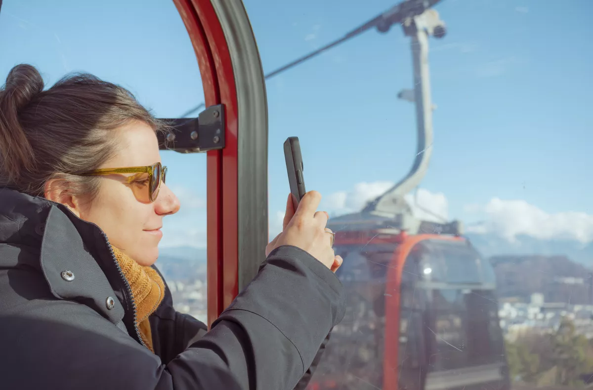 Woman taking a photo of the mountains from a gondola cable car