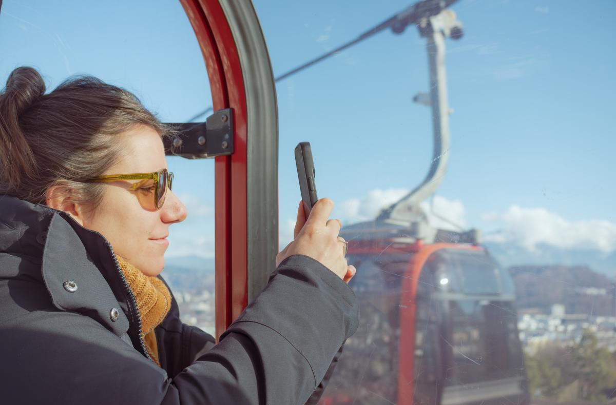 Woman taking a photo of the mountains from a gondola cable car