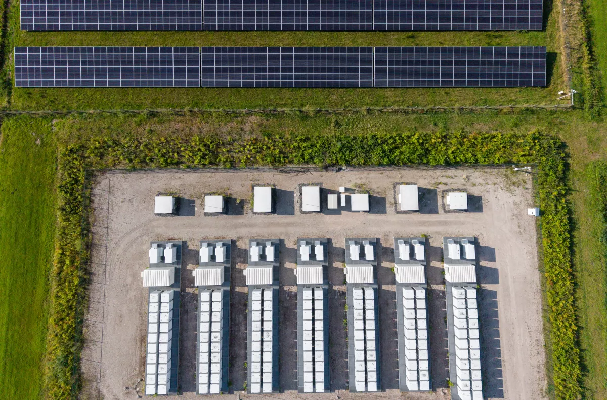 Aerial view of a large-scale solar farm featuring extensive rows of photovoltaic panels and a battery energy storage system in the rural landscape of Wanneperveen