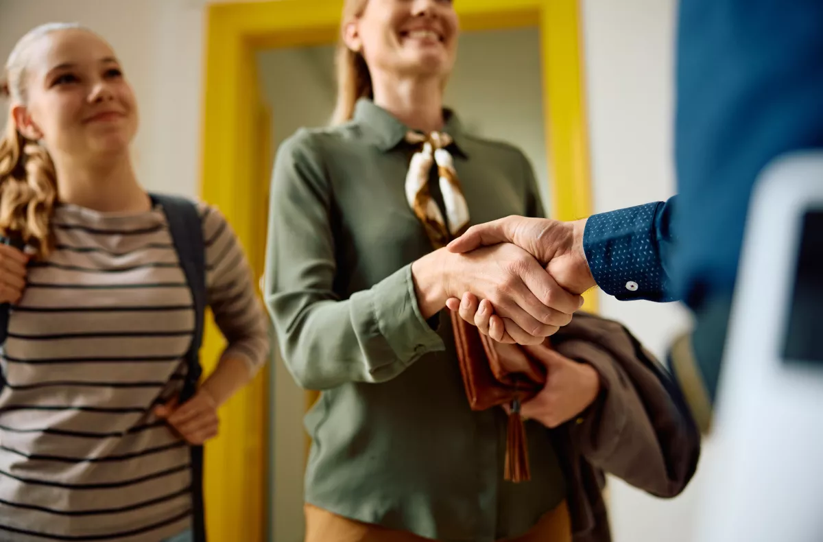 Two parents shaking the hand of a teacher