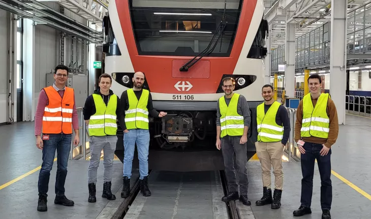 Six men stand in front of an SBB train