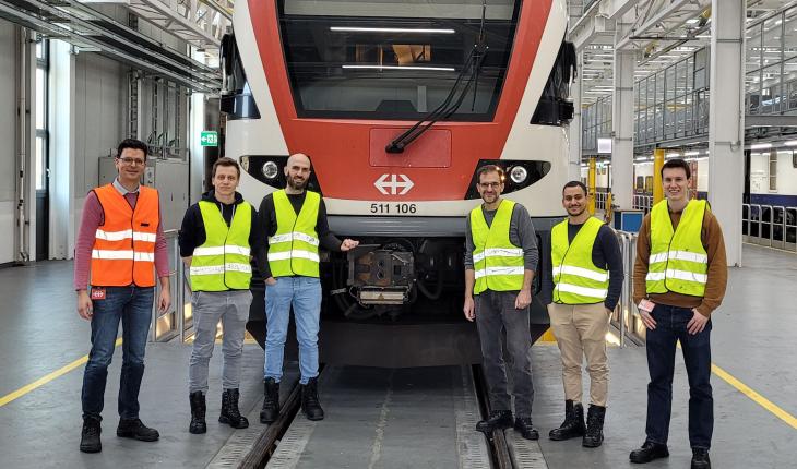 Six men stand in front of an SBB train