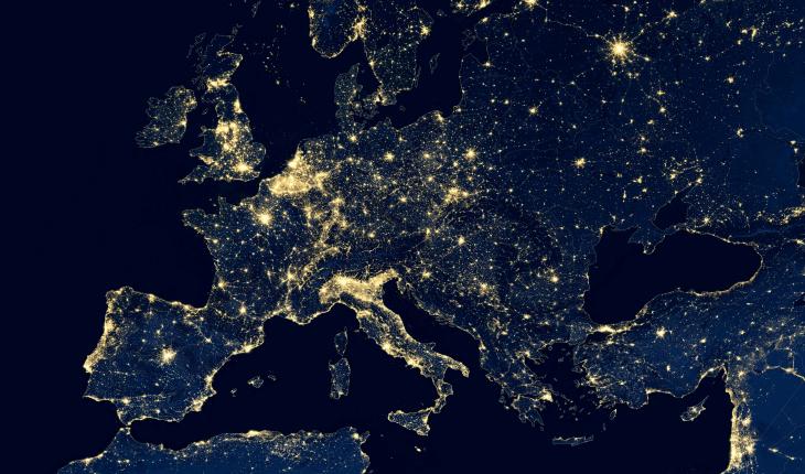 An aerial night view of Europe, showing the dense concentration of the electricity network.