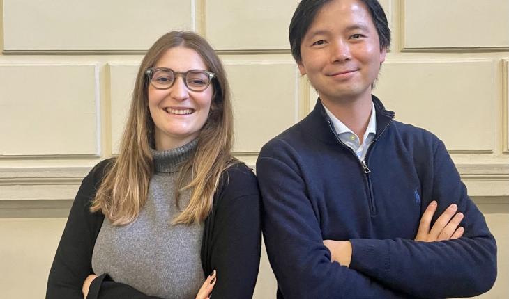 A woman and a man smile confidently at the camera, shoulder to shoulder.