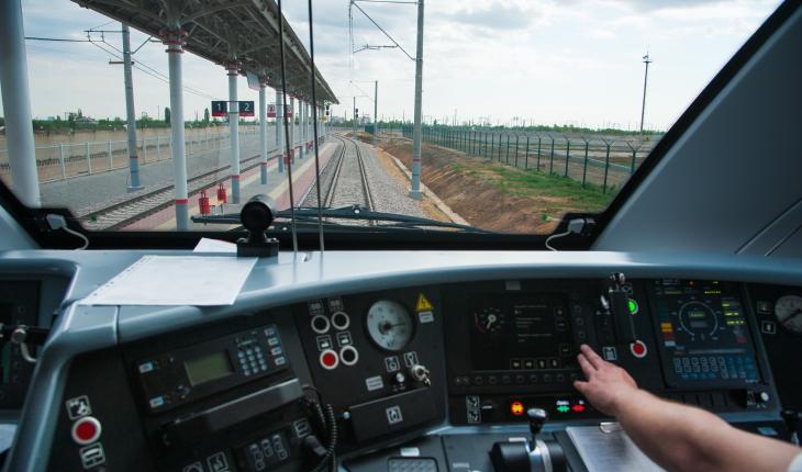 control panel of a train with a hand leaning forward to press a button