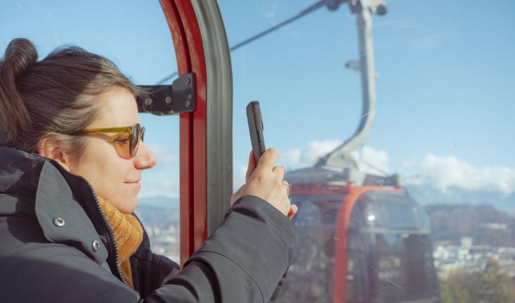 Woman taking a photo of the mountains from a gondola cable car