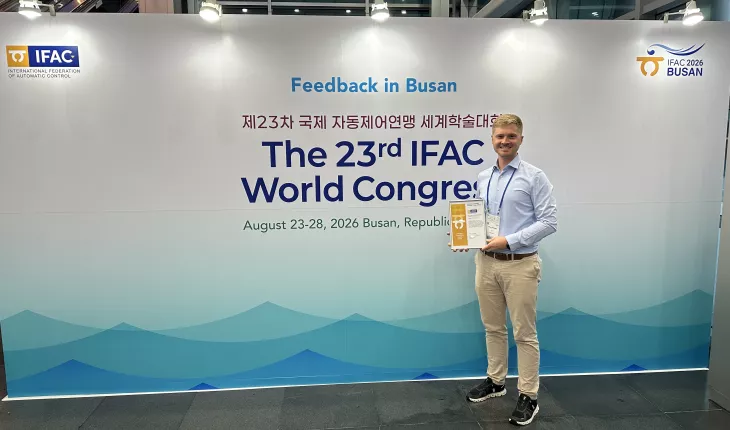 Lukas Ortmann holds his award next to the IFAC world congress entrance