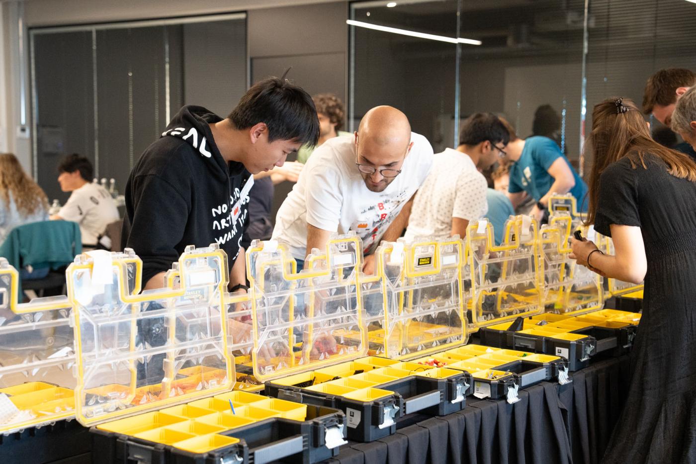 Two men bend over an assortment of boxes of Lego pieces.