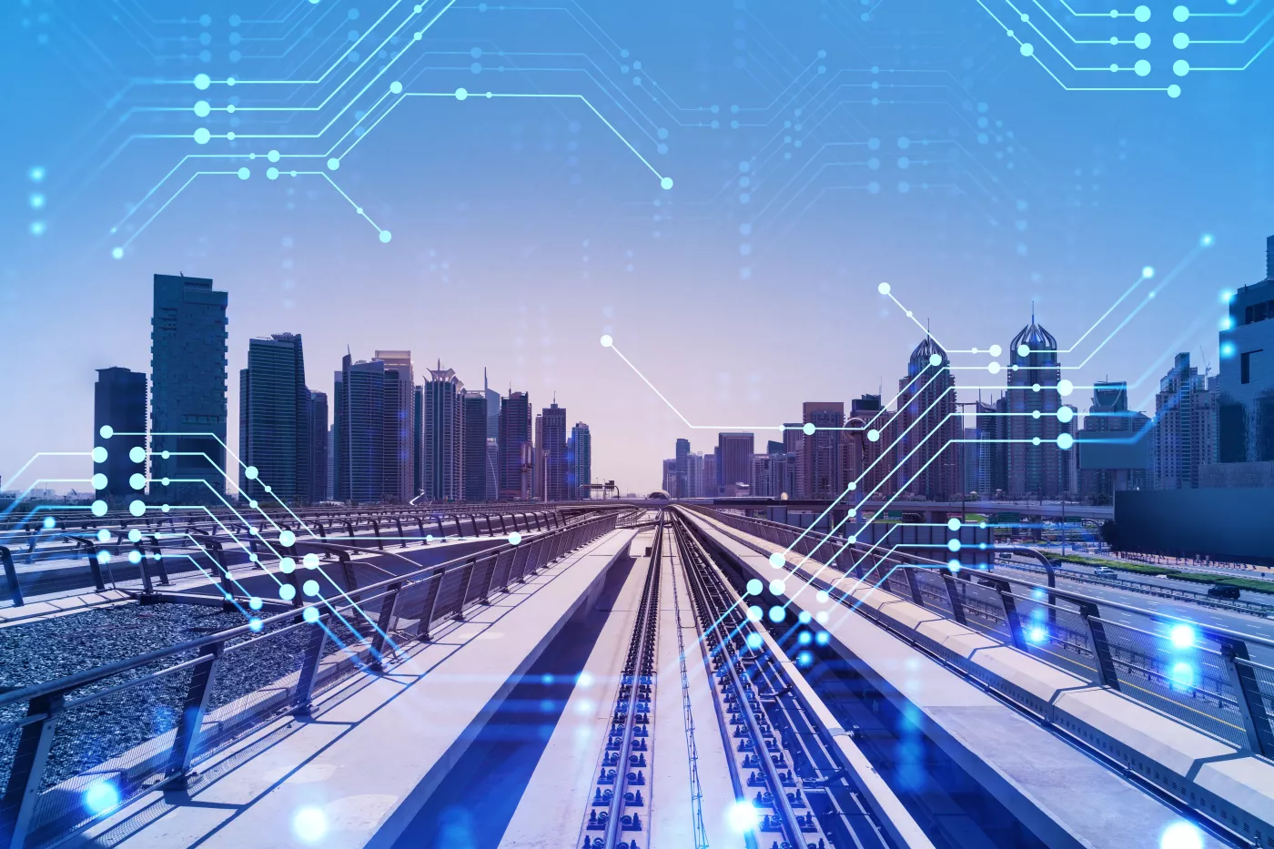 A photo of train tracks leading toward a city is overlaid with circuit board symbols. 