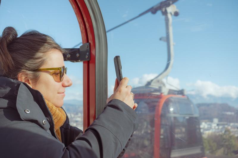 Woman taking a photo of the mountains from a gondola cable car